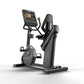 Matrix black stationary recumbent exercise bike with digital display screen and gold accents, on white background
