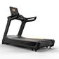Black motorized treadmill with digital touchscreen display, orange accent stripe, and dual grab handles on white background