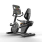 Matrix black recumbent exercise bike with digital console display, backrest, and foot pedals on white background