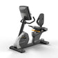 Matrix black and gray recumbent exercise bike with digital console, padded seat, and footrest on white background