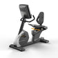 Matrix black and gray recumbent exercise bike with digital console, padded seat, and foot pedals on white background