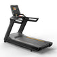 Black commercial treadmill with digital display console, running deck, and handles on white background