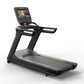 Black and gray commercial treadmill with integrated touchscreen display, gold accents, and cushioned running deck on white ba