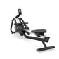 Black and silver rowing machine with digital display console, foot pedals, and black padded seat on white background