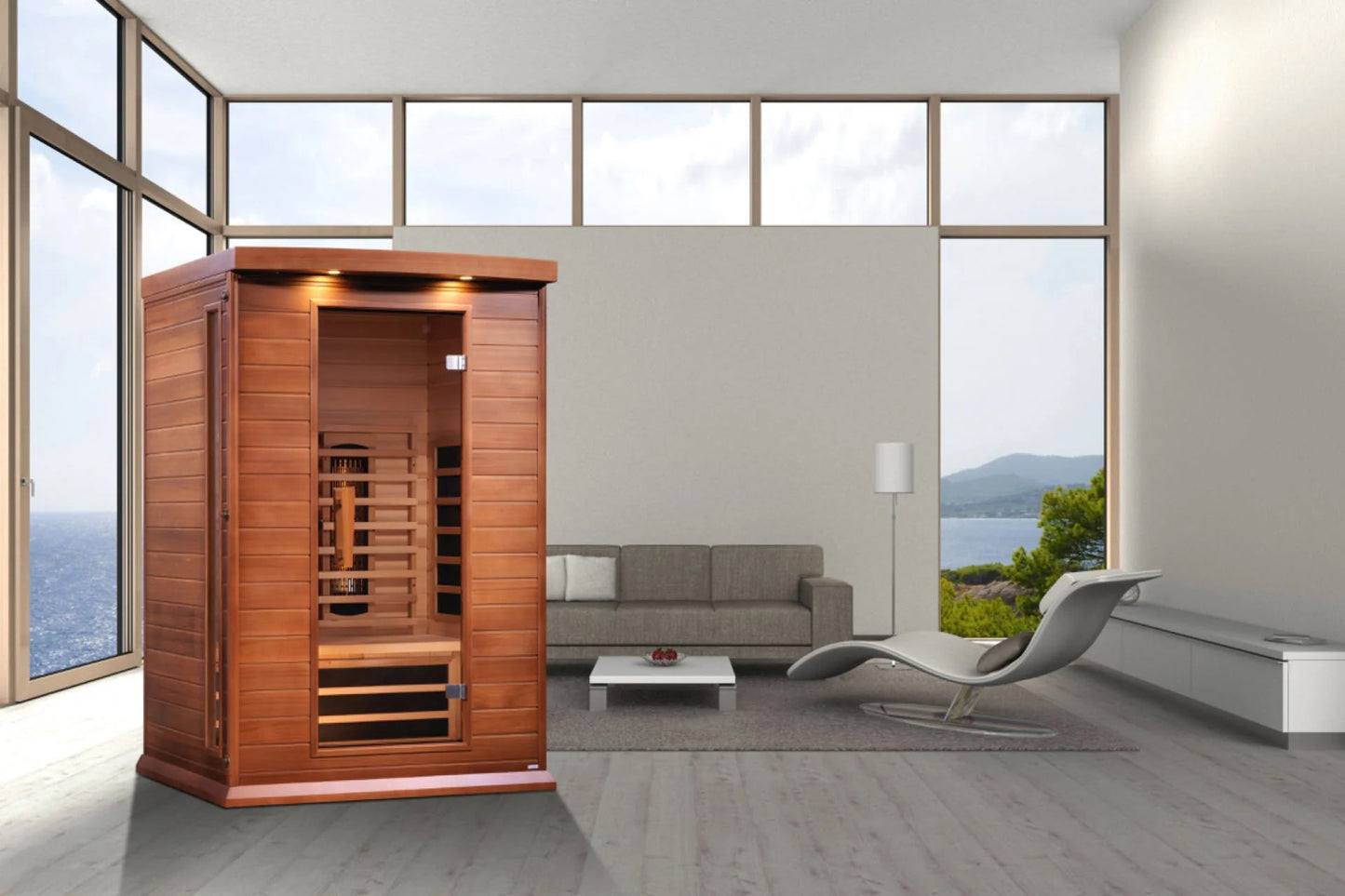 Red cedar infrared sauna cabin with glass door and front-facing heater, displayed in modern living room with ocean view