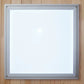 Gray aluminum-framed sauna control panel with white display screen on wooden wall