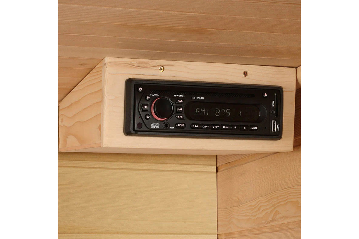 Black digital car stereo with red dial and display mounted in light wood panel on wooden sauna wall