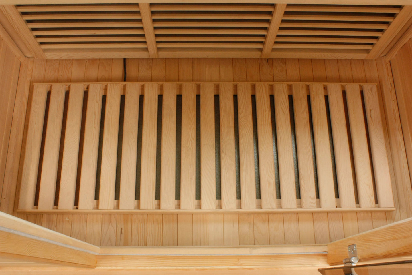 Natural wood sauna interior with slatted bench seating and horizontal ceiling vents, overhead view