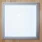 Silver-framed mirror with white reflective surface mounted on wooden wall background