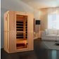 Light wood infrared sauna cabin with glass door and interior bench seating, displayed in modern living room setting