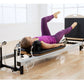 Woman in purple workout attire using Merrithew SPX Home Pilates Reformer with black and silver frame in studio setting