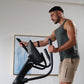 Man wearing charcoal tank top using black NordicTrack AirGlide 16 elliptical machine indoors