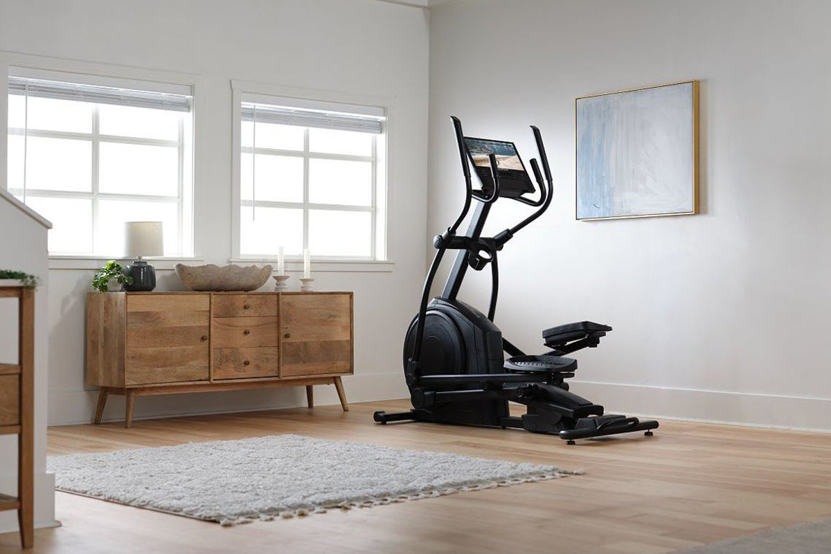 Black elliptical machine with dual handles and digital display in home gym setting