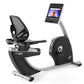 Black and silver recumbent exercise bike with mesh backrest, digital display monitor, and attached tablet holder on white bac