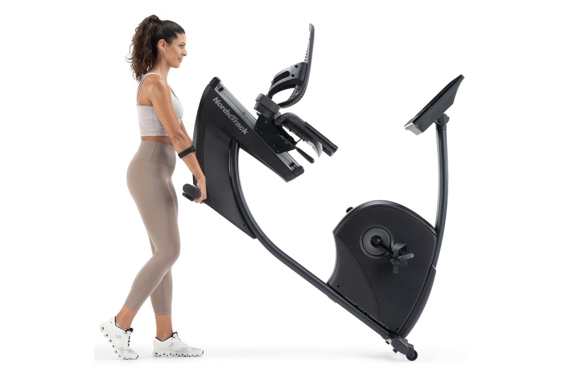 Woman using black NordicTrack recumbent exercise bike with digital display and adjustable seat, shown from side view on white