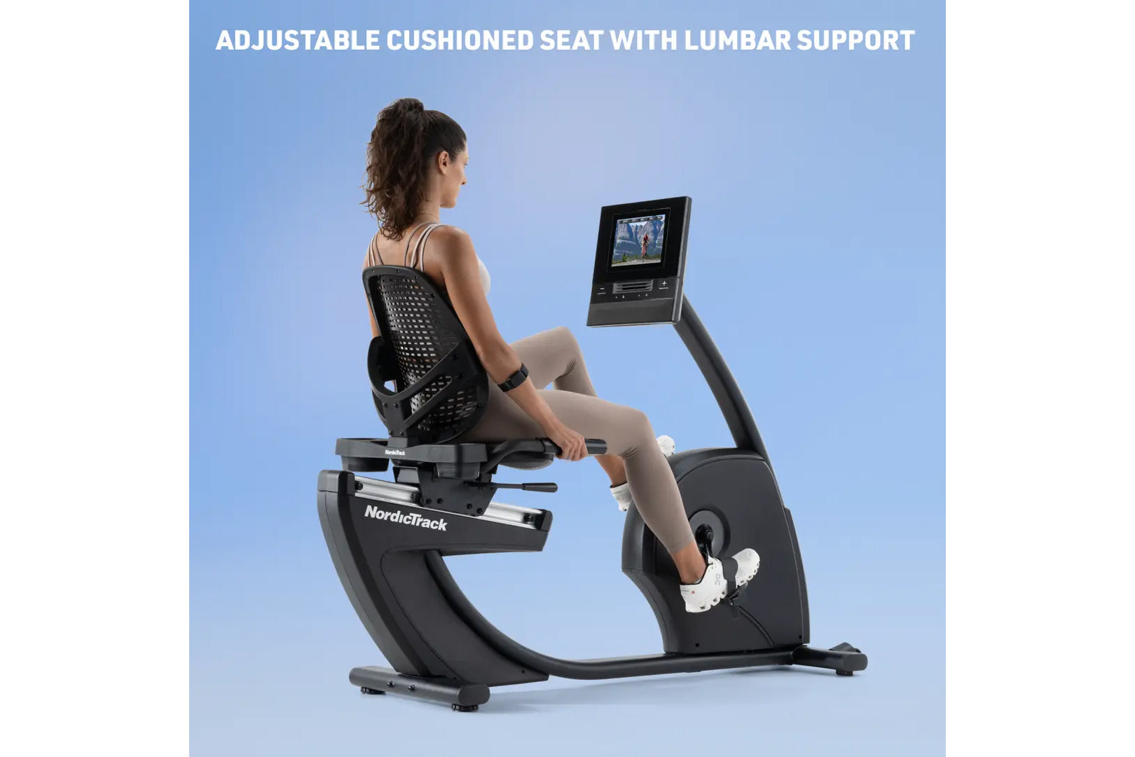 Woman seated on NordicTrack black recumbent exercise bike with perforated backrest, digital display, and adjustable cushioned