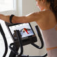 Woman wearing lavender sports bra using NordicTrack AirGlide 14i elliptical with digital display screen showing workout metri