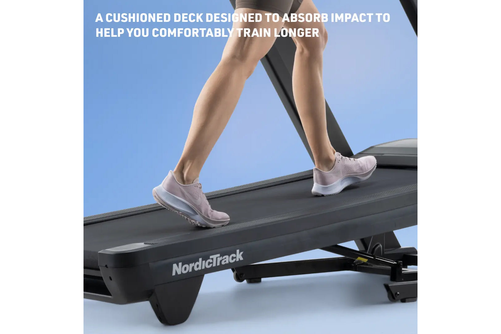 Person wearing pink sneakers running on NordicTrack treadmill with black cushioned deck against blue background