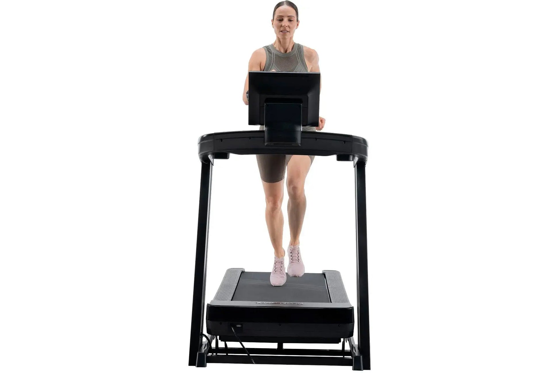 Woman wearing gray tank top and brown shorts running on black NordicTrack treadmill with digital display, shown from front on