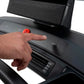 Hand pressing red emergency stop button on NordicTrack treadmill console with black control panel