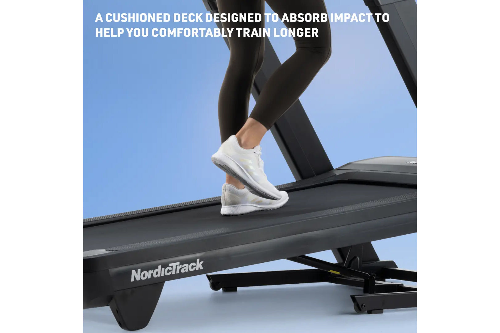 Person wearing white sneakers and black leggings running on NordicTrack treadmill with cushioned black deck against blue back