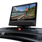 NordicTrack Commercial 1750 treadmill with black console displaying running video of person in orange shirt by mountain lake