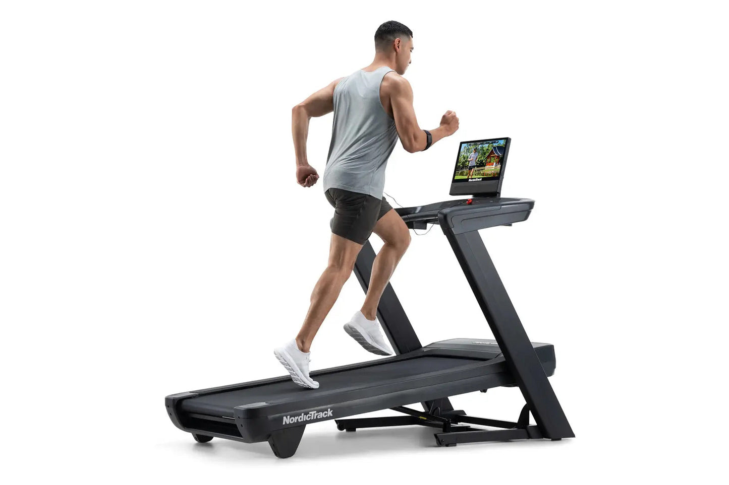 Man running on black NordicTrack treadmill with tablet display, wearing gray sleeveless shirt and black shorts