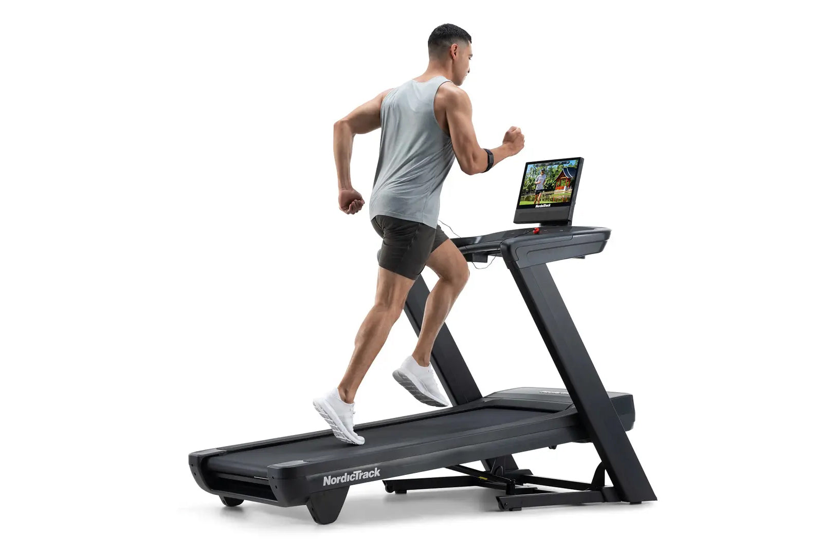 Man running on black NordicTrack treadmill with tablet display, wearing gray sleeveless shirt and black shorts