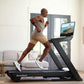 Man running on NordicTrack black treadmill with touchscreen displaying outdoor scenery in modern living room