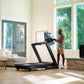Man using black NordicTrack treadmill with digital display in modern living room with large windows