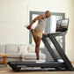 Man running on black NordicTrack treadmill with built-in screen in modern living room