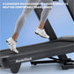 Person wearing white running shoes and gray leggings running on NordicTrack treadmill with cushioned black deck against blue 