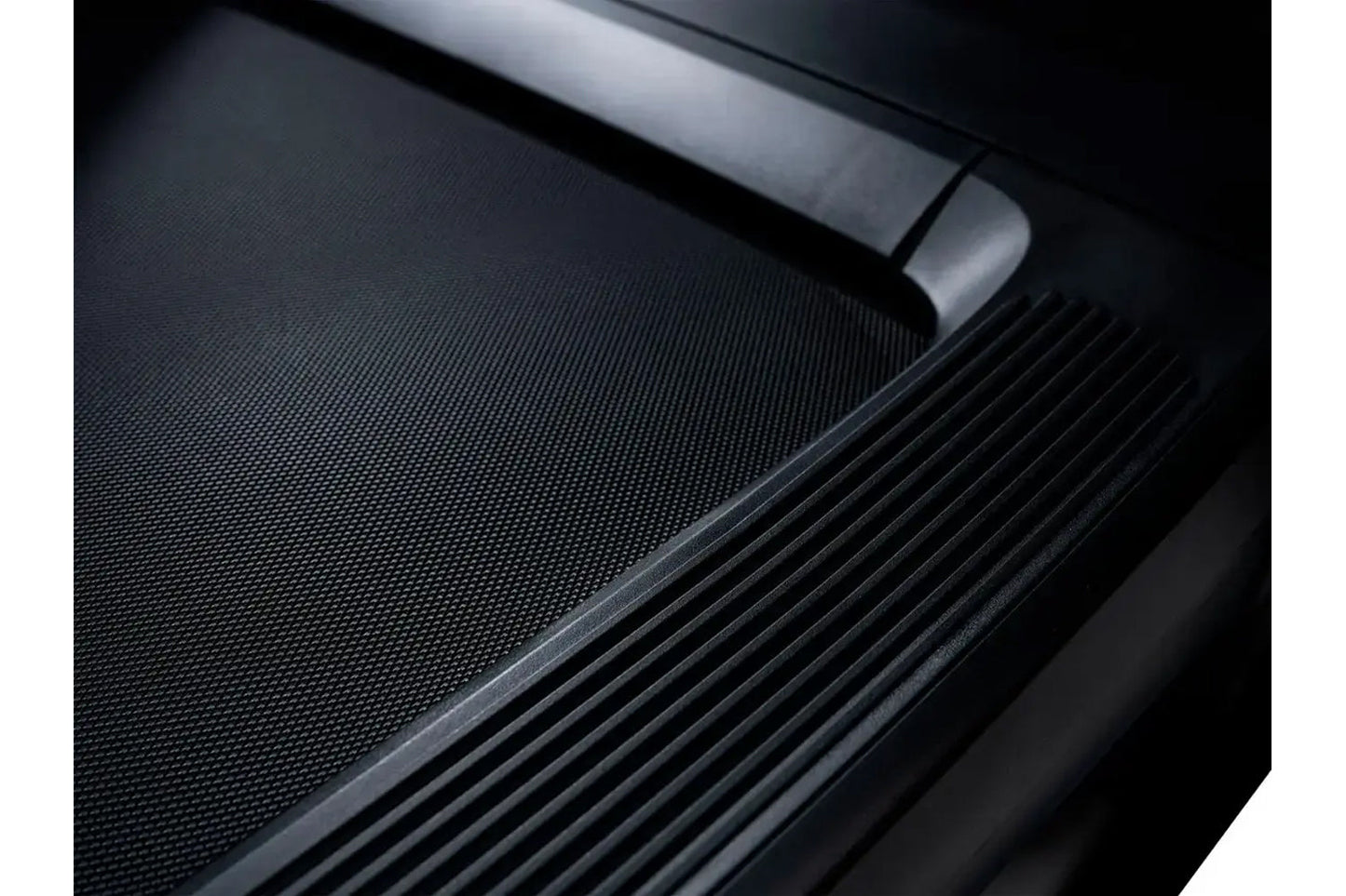 Black treadmill running surface with textured belt and metal handrail detail, flat lay view