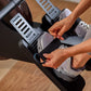 Hands gripping handlebar of black and gray rowing machine with textured foot pedals on wooden floor