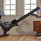 Woman in blue sports bra and beige leggings using black NordicTrack RW600 rowing machine with digital display in bright home 