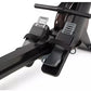 Black and gray rowing machine with dual foot pedals, black handlebar, and digital monitor display on white background