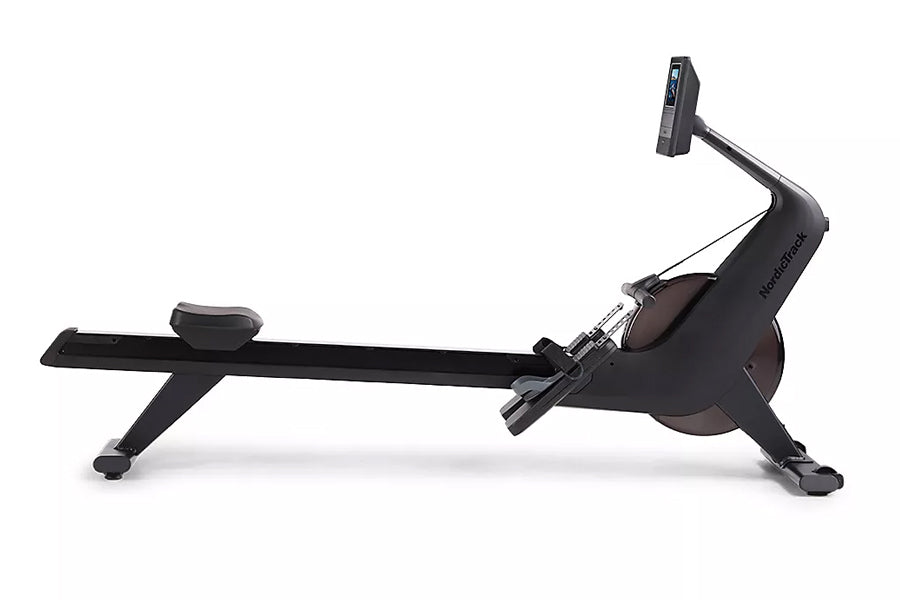 Black NordicTrack RW600 rowing machine with digital monitor, featuring extended seat rail and foot pedals, shown from side vi