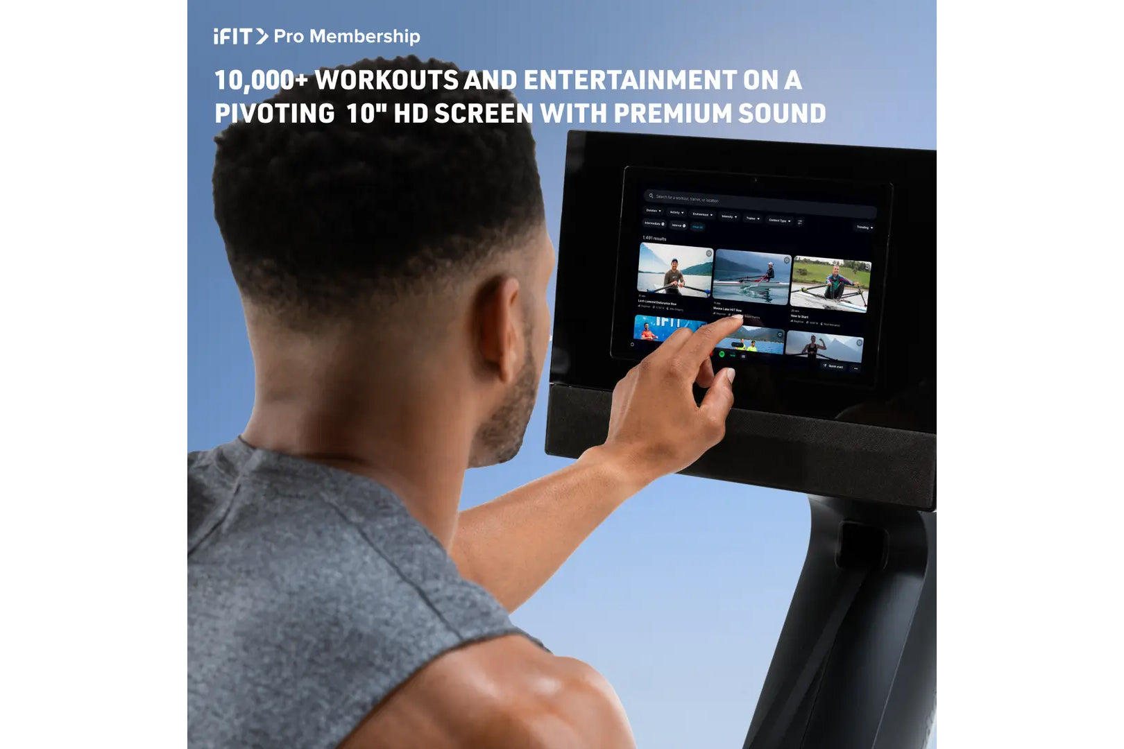 Man touching 10-inch HD touchscreen on NordicTrack rower displaying iFIT Pro workout library with multiple video classes