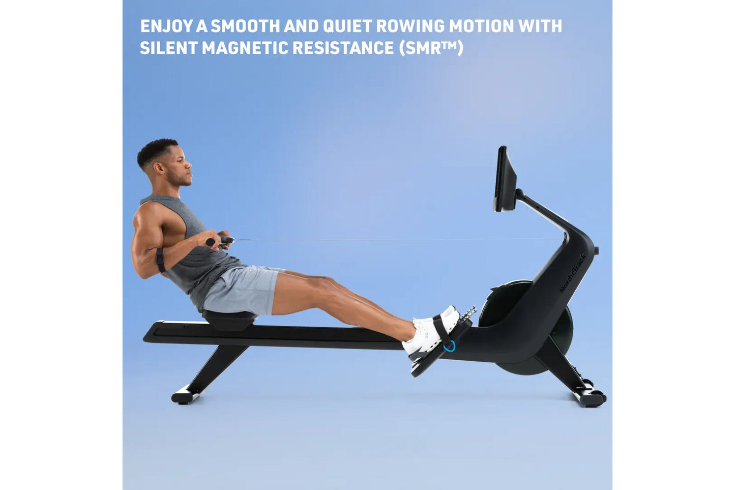 Man using black magnetic rowing machine with extended leg position on blue background