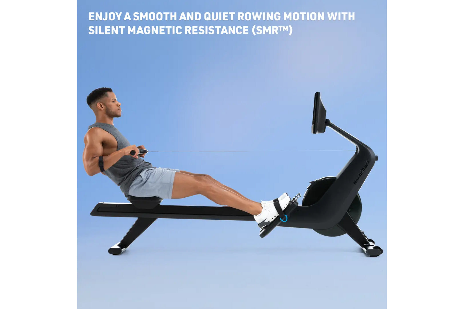 Man using black magnetic rowing machine with extended leg position on blue background