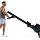 Man using black NordicTrack RW700 rowing machine, wearing gray tank top and light blue shorts