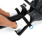 Person wearing white sneakers on black rowing machine foot pedals with adjustable straps
