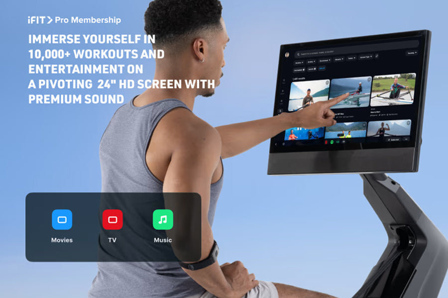 Man in gray tank top using NordicTrack RW900 rowing machine with 24" HD pivoting touchscreen displaying iFIT Pro workout cont