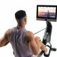 Man using black and gray NordicTrack rowing machine with touchscreen display showing fitness class, worn against white backgr