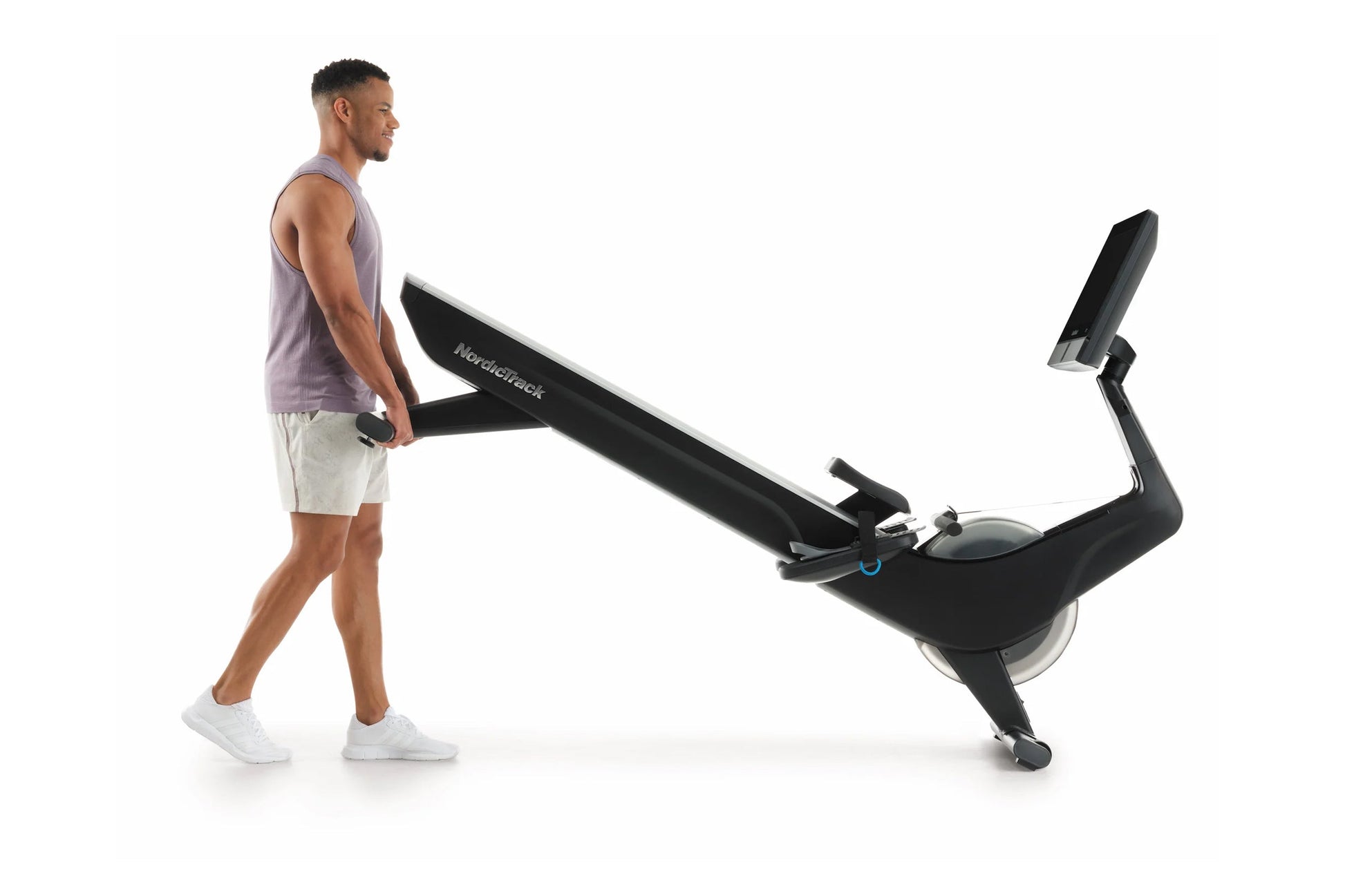 Man using black NordicTrack stationary rowing machine with digital display on white background