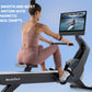 Woman in pink sports bra and leggings using black NordicTrack rowing machine with tablet displaying water rowing scene agains
