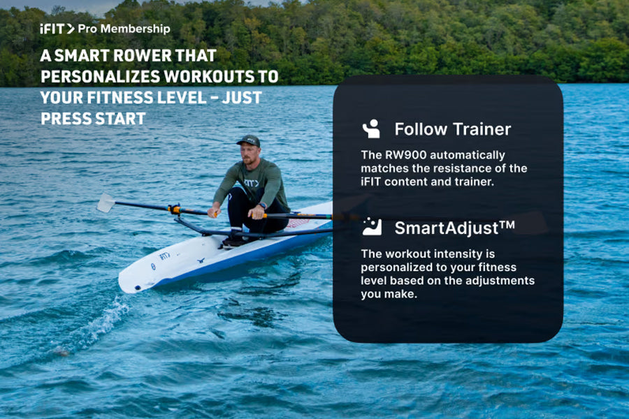 Man in gray shirt rowing on white and teal rowing machine in blue ocean water, with forested shoreline in background