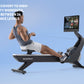 Man using black NordicTrack rowing machine with attached screen display on blue background
