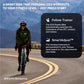 Cyclist riding teal and black studio bike outdoors on mountain road, wearing green jacket and burgundy leggings with helmet a