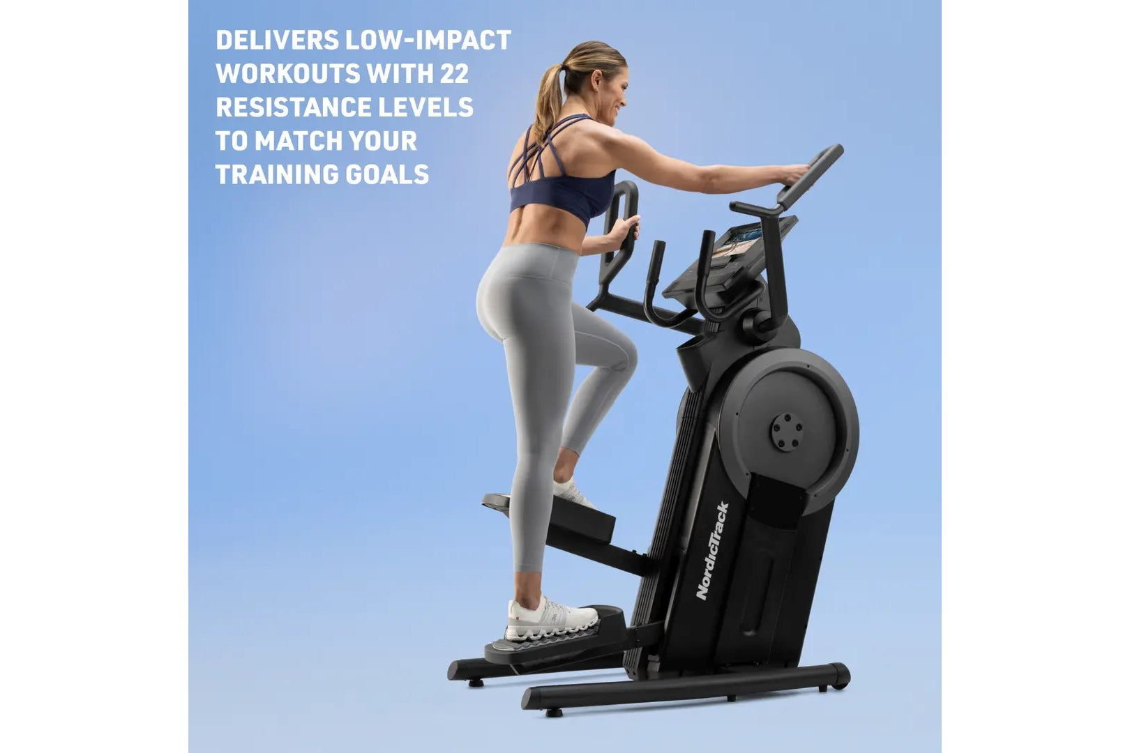 Woman using black NordicTrack step climber with digital display, wearing navy sports bra and gray leggings, on blue backgroun